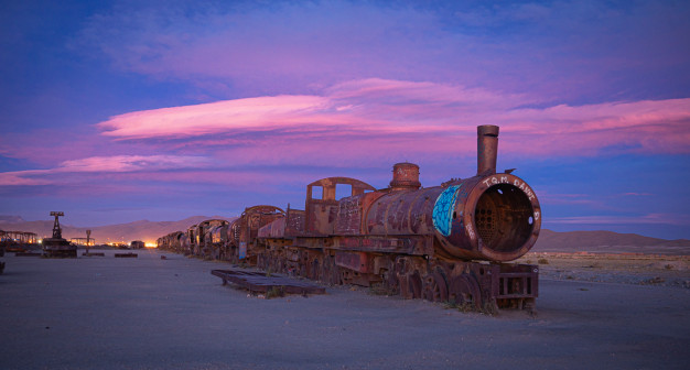 Rusty train under twilight sky in desert landscape.