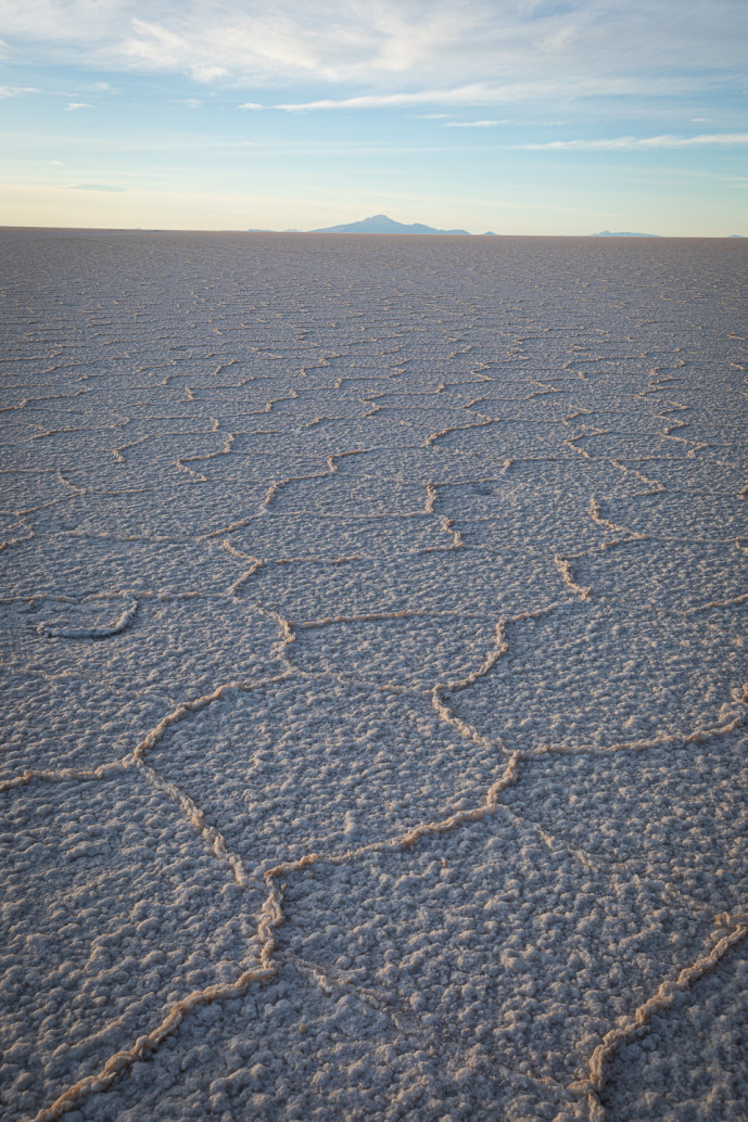 Vast salt flats with hexagonal patterns at sunset.