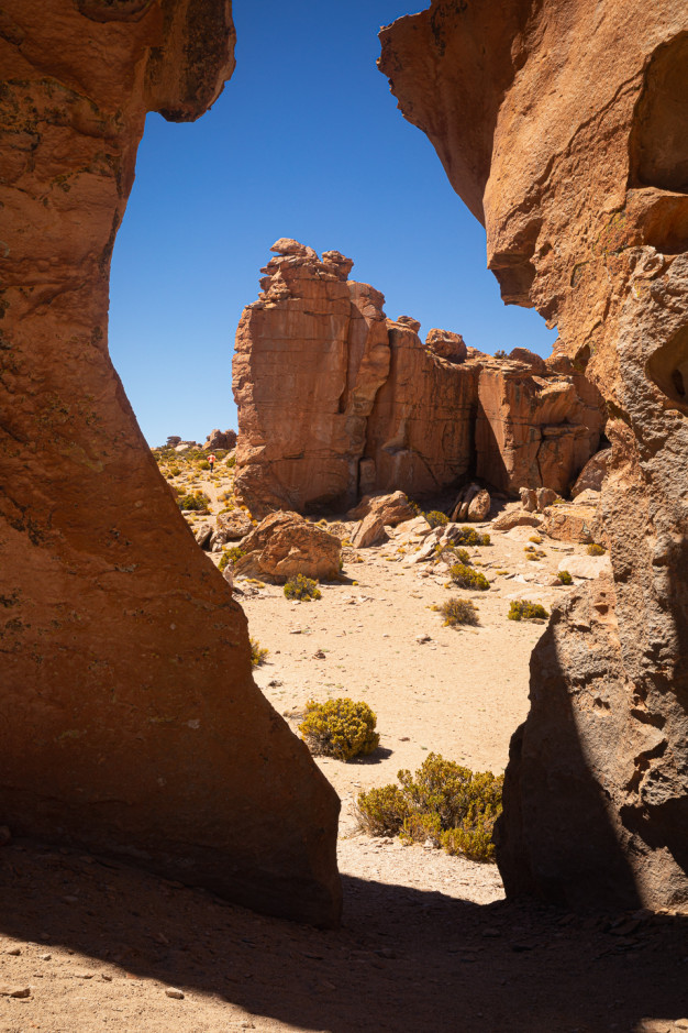 Rocky desert landscape with natural archway and blue sky.