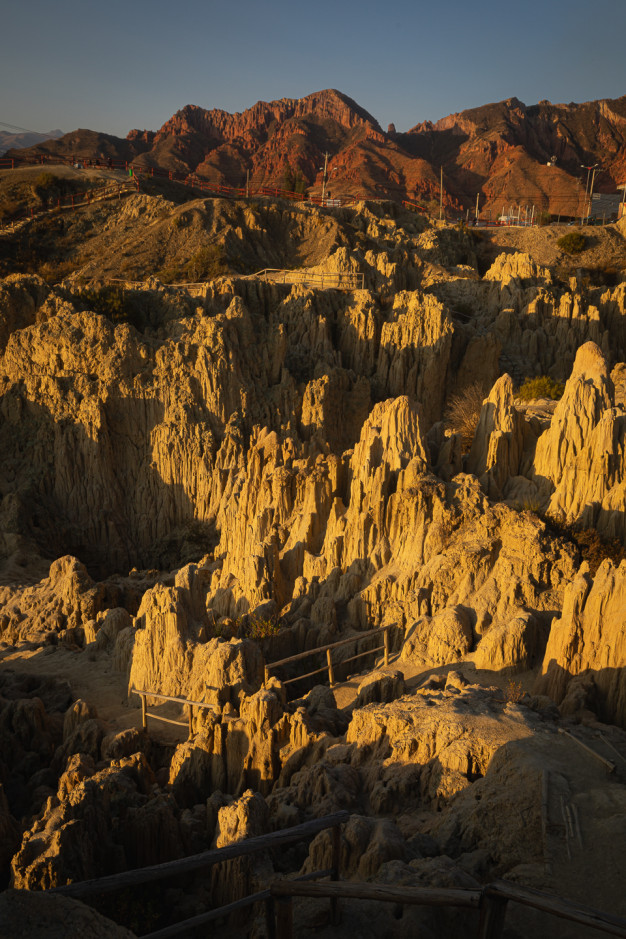 Sunlit eroded canyon with walking paths at sunset.
