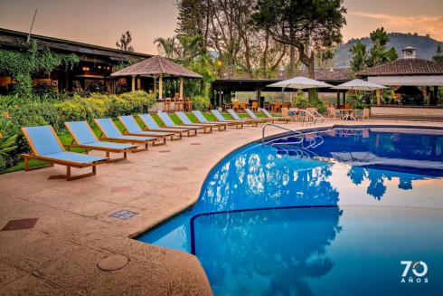 Tranquil hotel pool at dusk with lounge chairs.