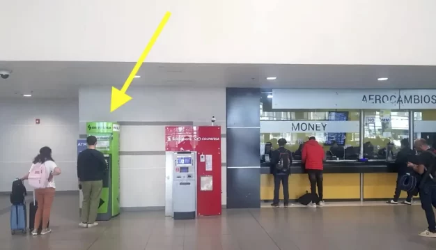Intérieur de l'aéroport avec des distributeurs automatiques de billets et un comptoir de change.
