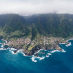 Aerial view of coastal village with cliffs and ocean.