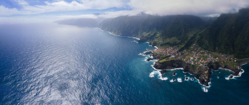 Aerial view of coastal village with mountains and sea.