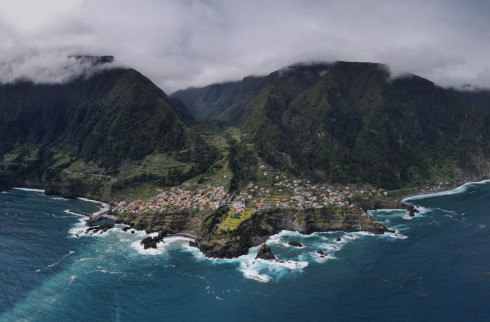 Coastal village with mountains and ocean, aerial view.