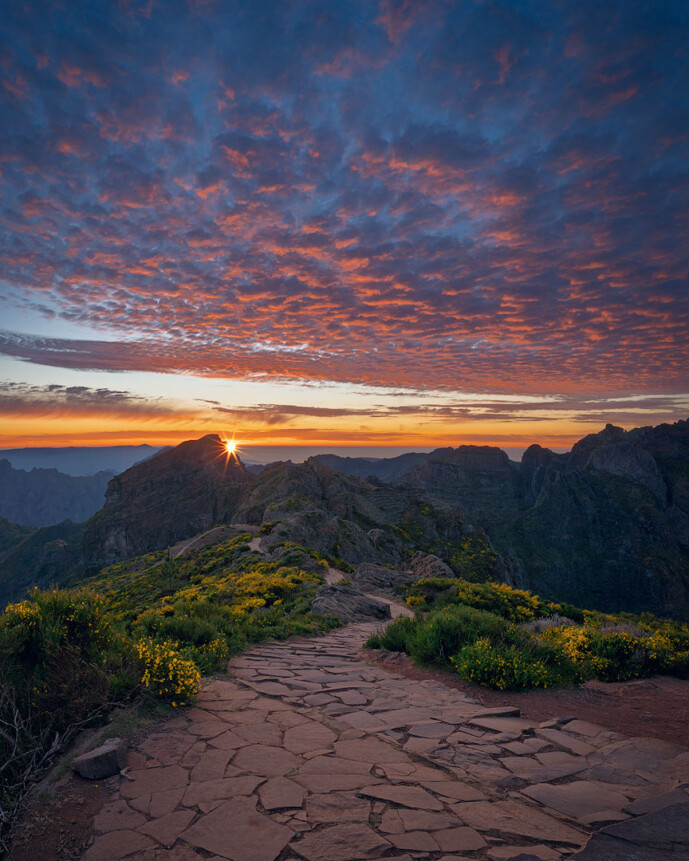 Mountain trail at sunrise with colorful sky and clouds